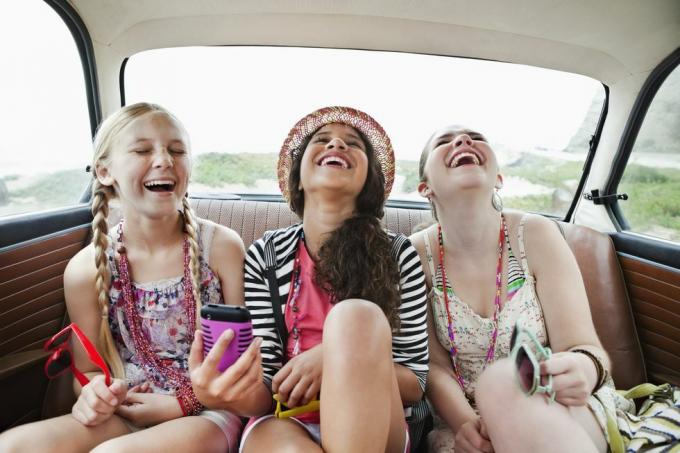 три девојке се смеју на задњем седишту возила