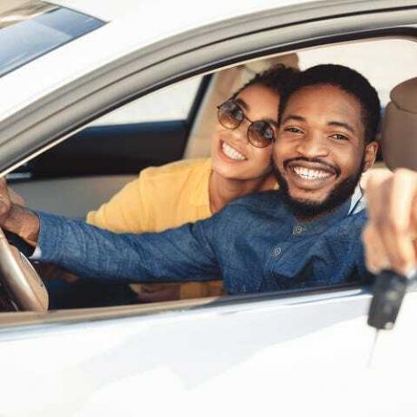 афроамерички супружници који показују нови кључ од аутомобила који седи у аутомобилу