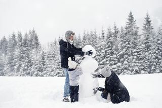 трочлана породица гради снежног човека у снегу