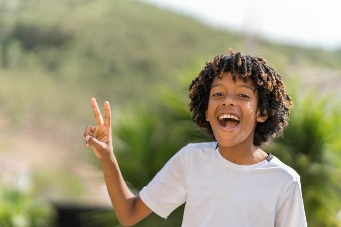 10-годишњи Афроамериканац који се гласно смеје док прави знак мира