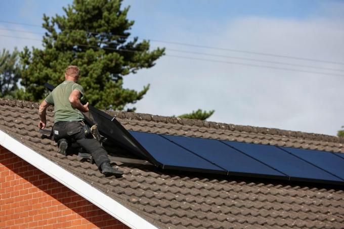 х0цхн1 човек поставља кровне соларне панеле у домаћу инсталацију соларних панела у Великој Британији
