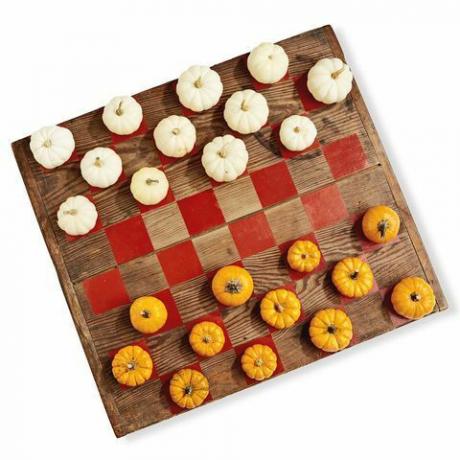 дрвена табла осликана попут игре за даме користећи мини бундеве у белој и наранџастој боји