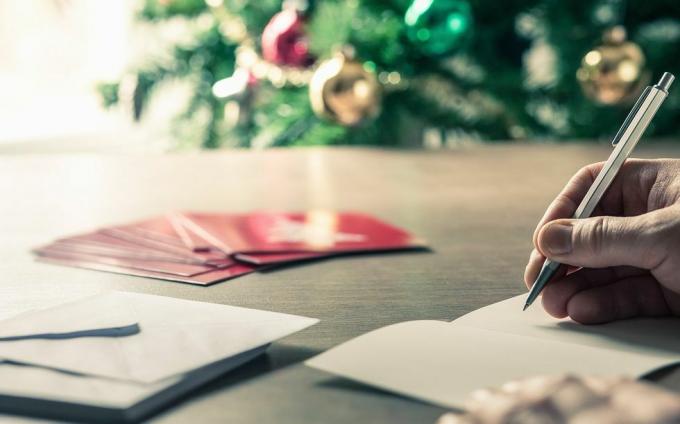 писање порука за божићне честитке испред празничног дрвета