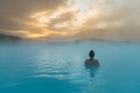 задњи поглед на жену која стоји у плавој лагуни, Исланд