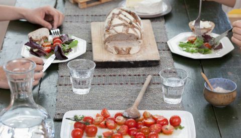 Изблиза пара који ручају за столом с парадајзом и хлебом