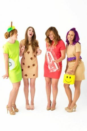 четири смејане жене у кратким хаљинама одевене као „даме за ручак“, једна носећи жуту кутију за ручак смајлића